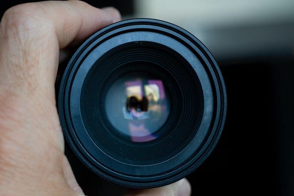 Close up image of a hand holding a camera lens, displaying video marketing