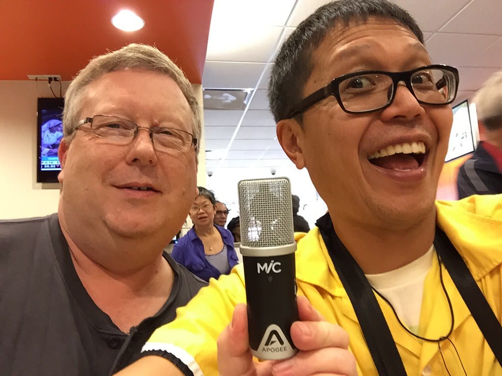 Man taking a selfie smiling with a  microphone used for podcasts in his left hand