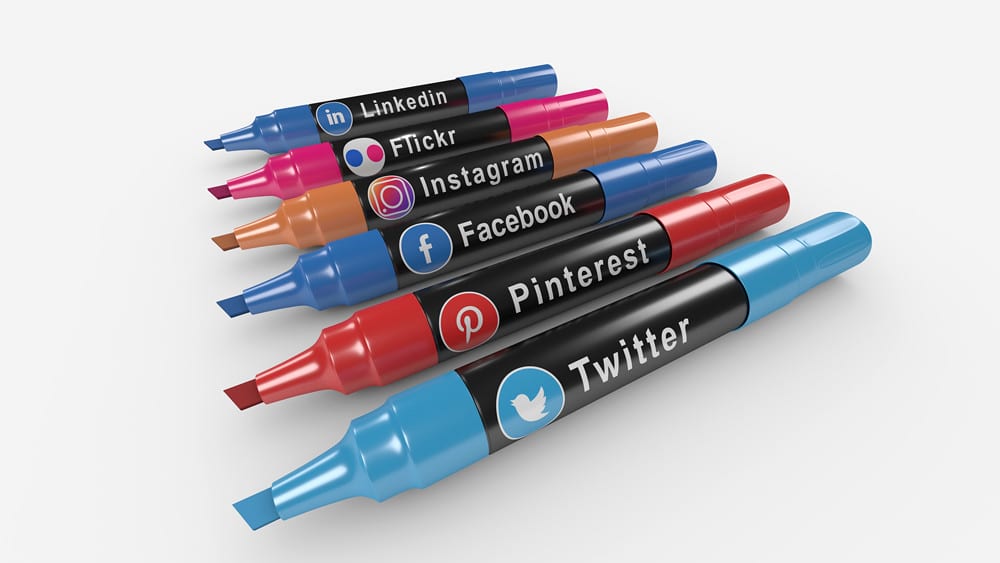 This image is of a row of colorful markers with each one containing a different social media logo printed on them.