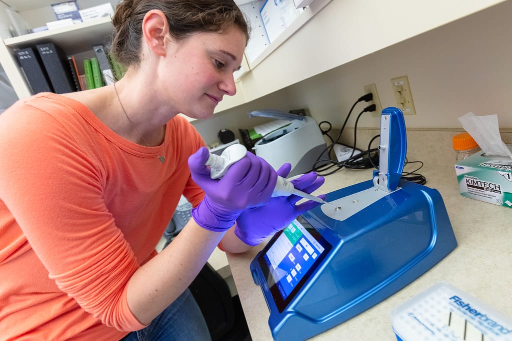 A women using a DNA testing machine in a laboratory