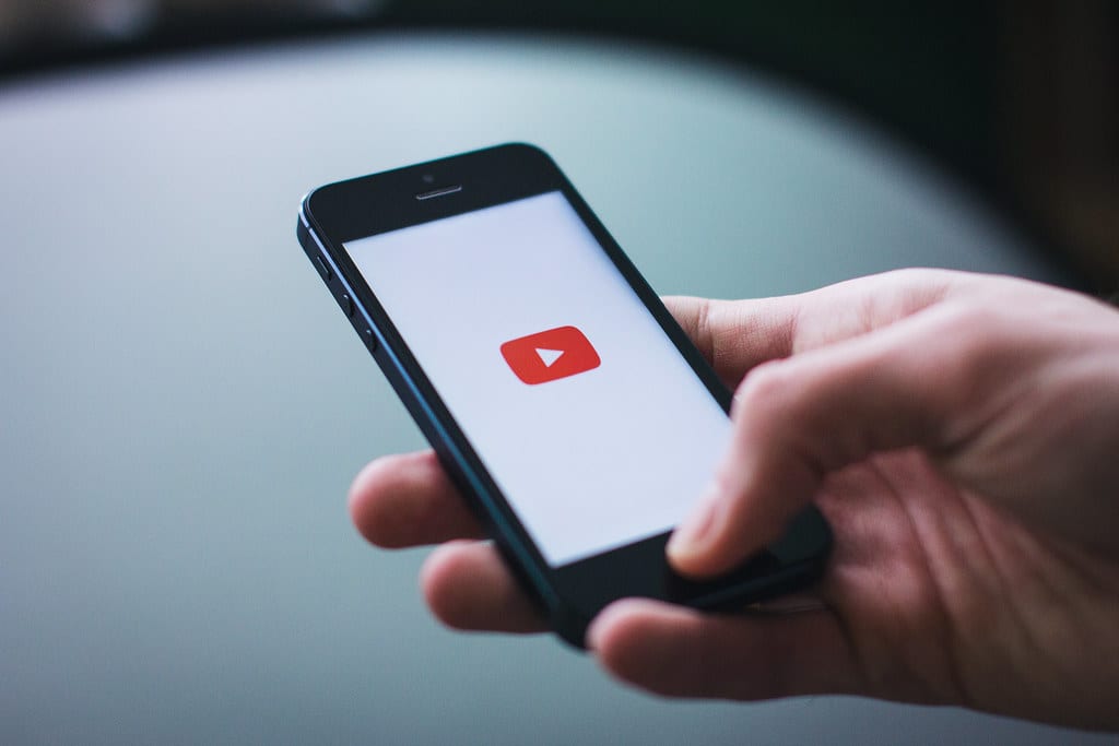 Image of a hand opening the YouTube app on a smartphone