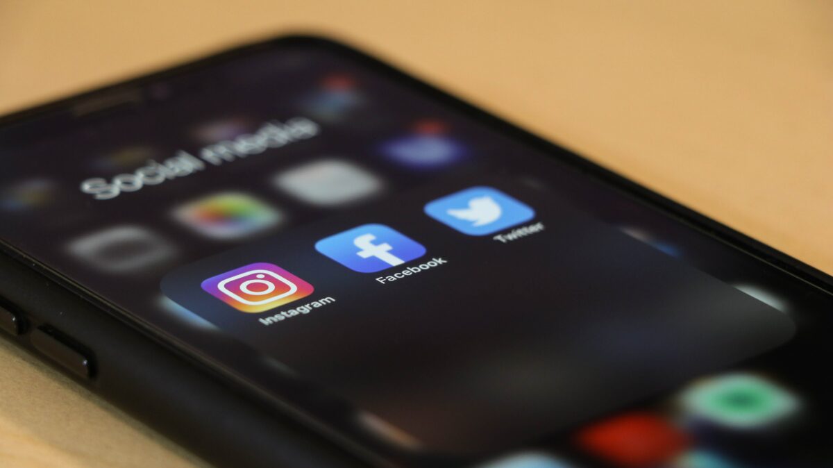 Image of a phone displaying icons for social media apps, Instagram, Facebook, and Twitter