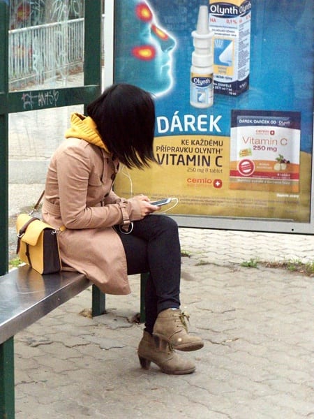 Image of female sitting at bus stop ignoring advertisement
 