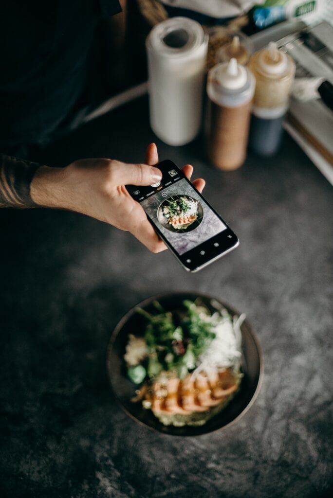 Image of a Food Influencer taking pictures of a dish with an iPhone 