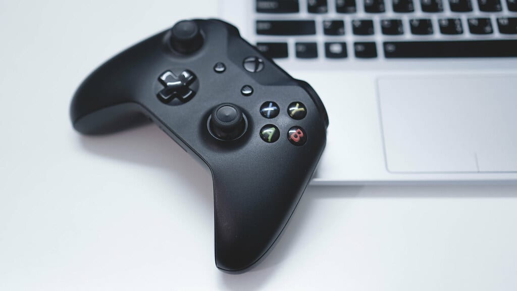 An image of a  X-Box One Controller resting on an Mac Book. 