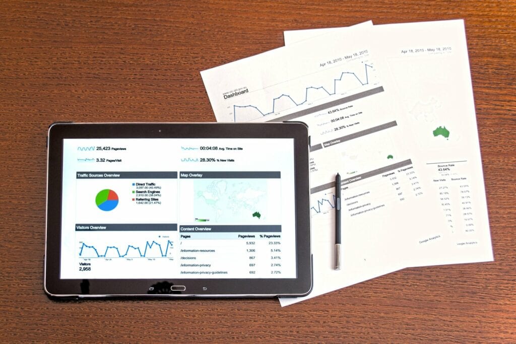 Digital Marketing analytics shown on a tablet and paper both displaying performance metrics 