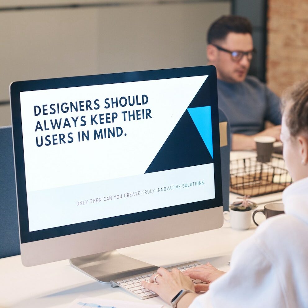 Close-up of a female UX designer sitting in front of a computer screen with the sentence "Designers should always keep their users in mind."