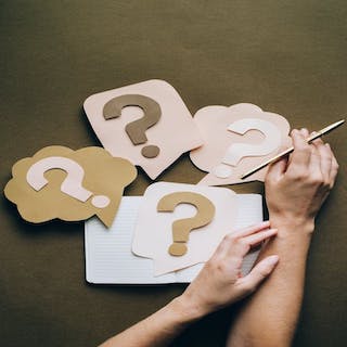 Image of question marks crafted on paper with two hands 